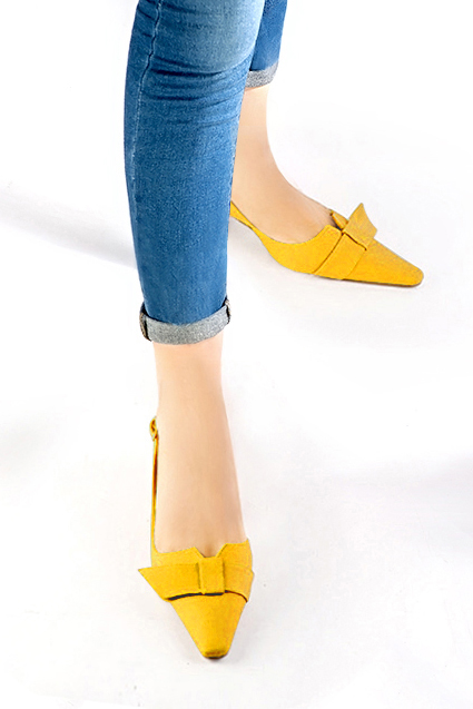 Women's yellow elegant slingback heels, with a bow on the front. Tapered toe. Medium spool heels - Worn view